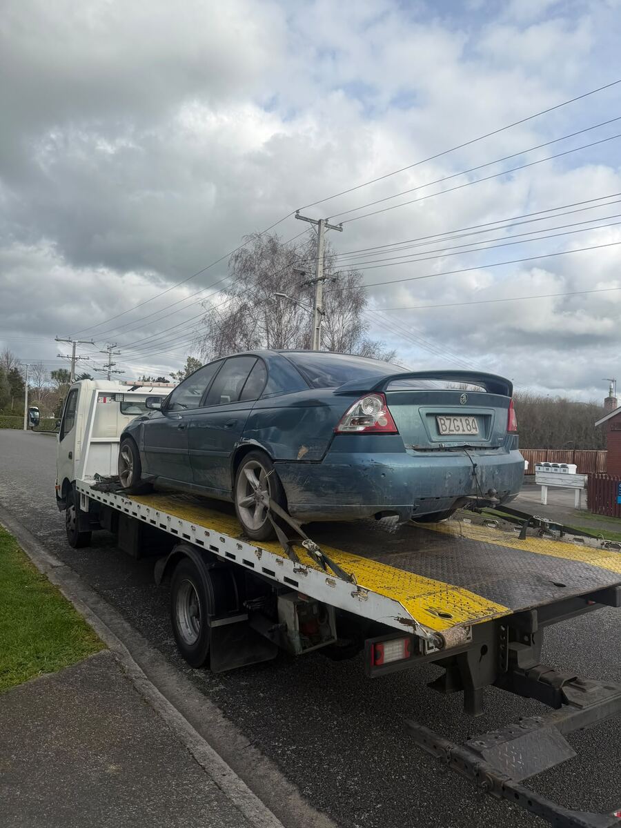 Blue sedan loaded on a flatbed tow truck during same-day car removal in South Auckland