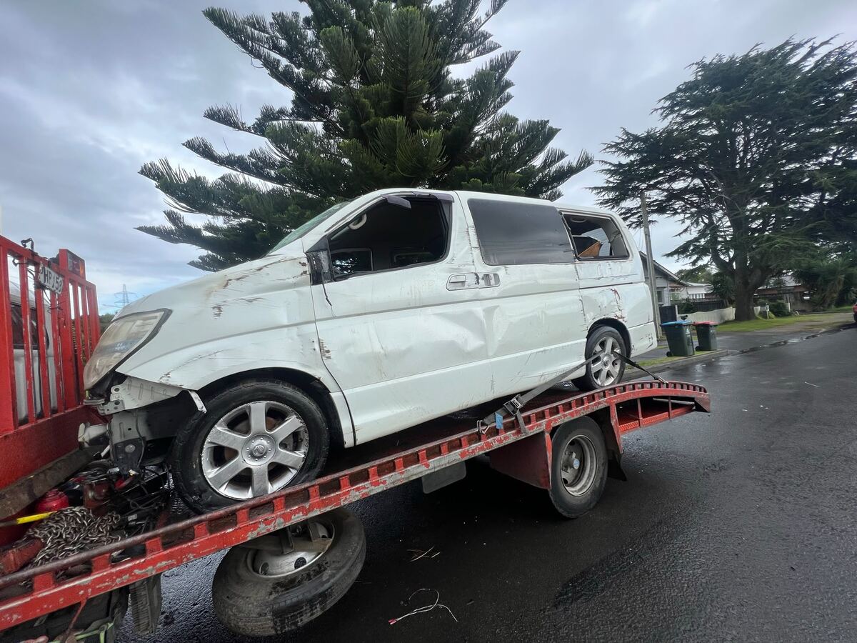Crashed white van loaded on a tilt-tray truck for scrap car removal in South Auckland